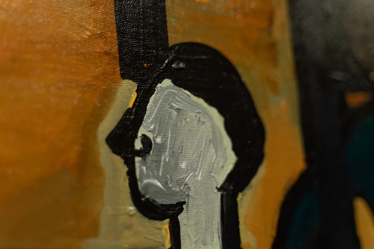Detail of a single face painted in pale strokes against the dark