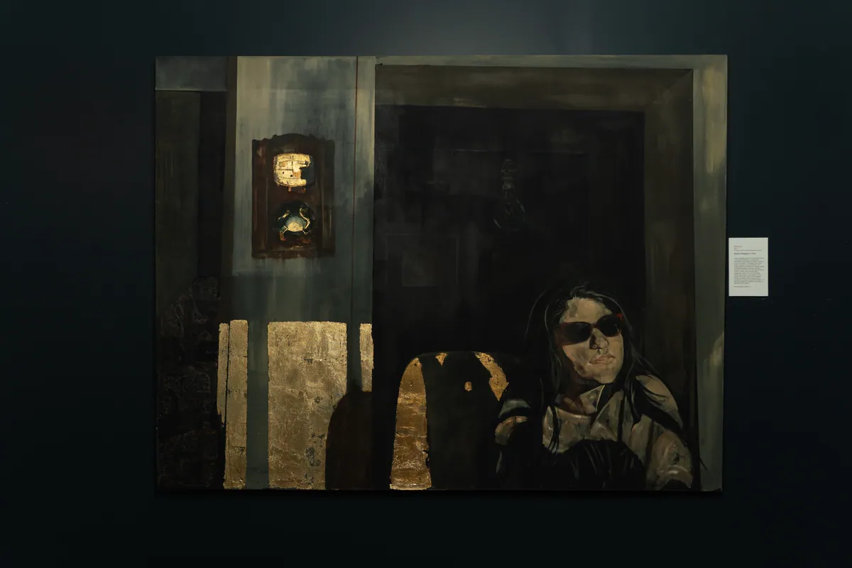The painting on a dark navy wall at TolHouse beside its wall label
