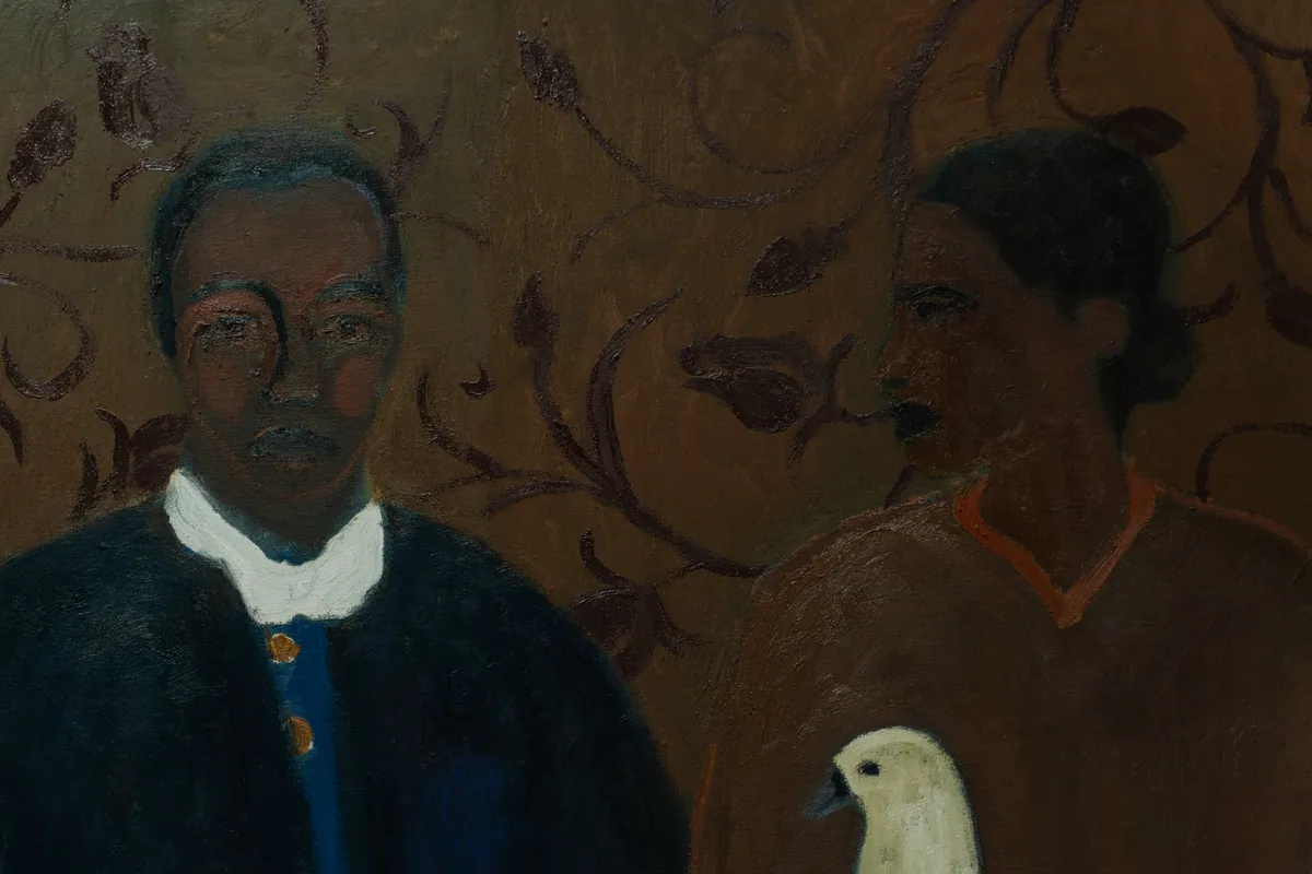 Detail of the two faces against the leaf-patterned ground